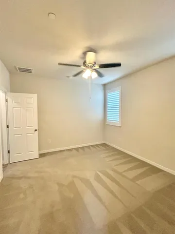 a view of an empty room and chandelier fan