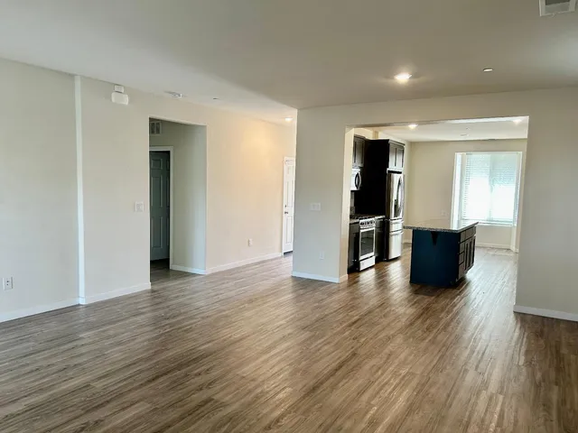 a view of a big room with wooden floor and windows