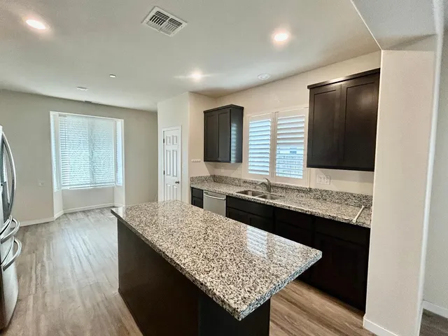 a kitchen with granite countertop wooden cabinets and a refrigerator