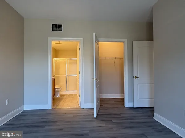 a view of an empty room with wooden floor and closet