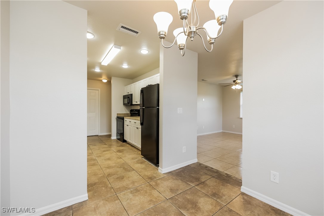 2607 30th Street Southwest Lehigh Acres, FL 33976 - Photo 7 of 16 a view of a kitchen with a refrigerator and a chandelier