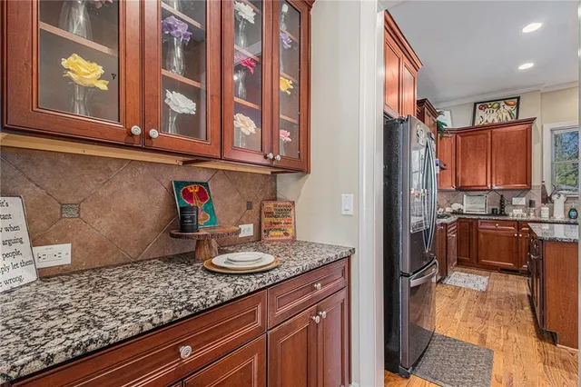 a kitchen with stainless steel appliances granite countertop a refrigerator a sink dishwasher a stove with wooden cabinets and floor