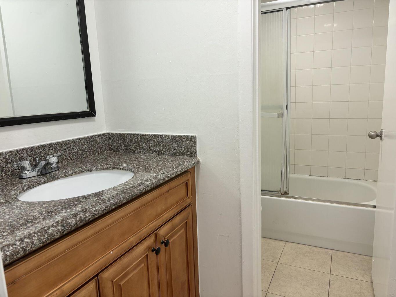 642 Northwest 13th Street, Unit 210 Boca Raton, FL 33486 - Photo 11 of 17 a bathroom with a granite countertop sink and a mirror