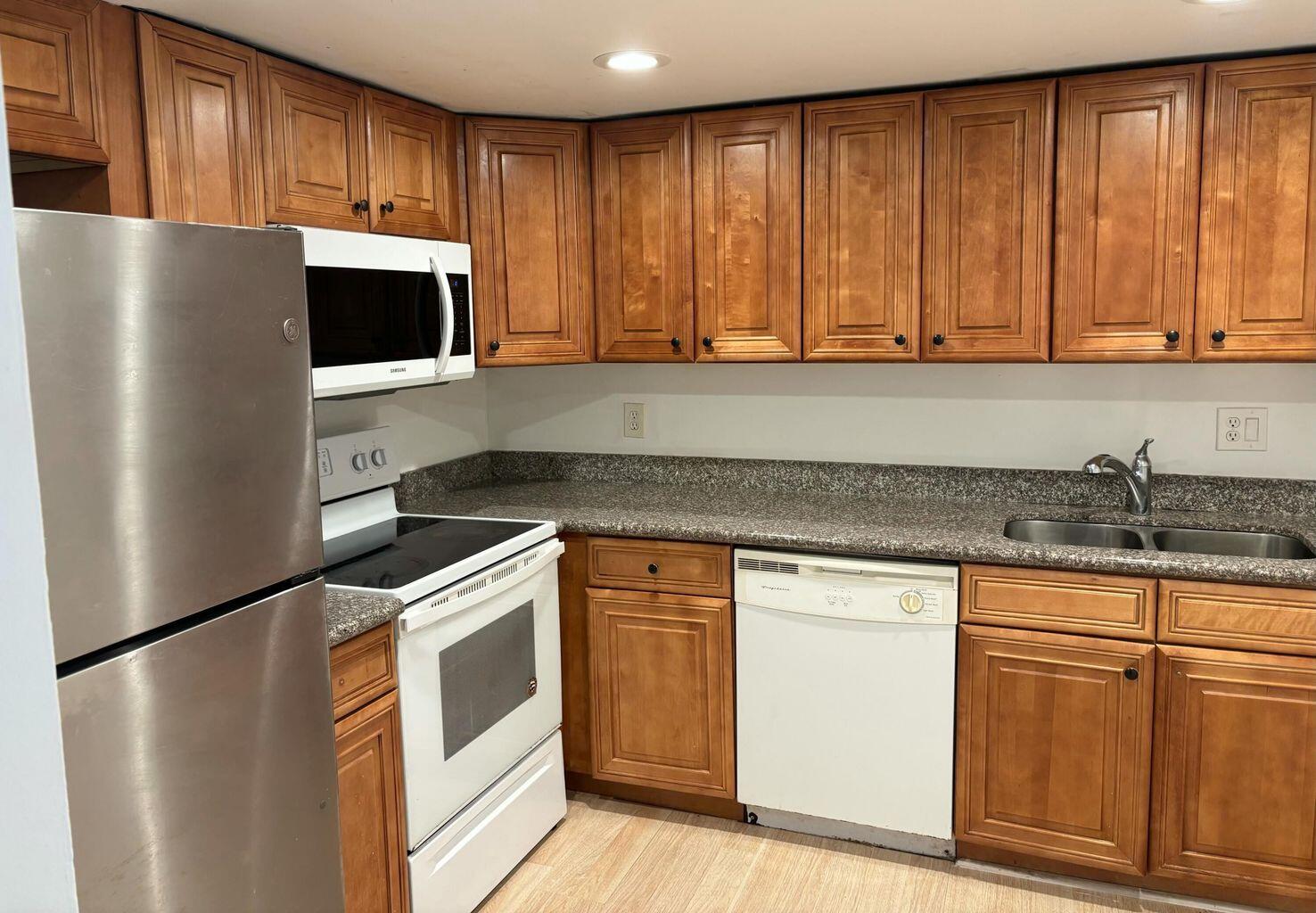 642 Northwest 13th Street, Unit 210 Boca Raton, FL 33486 - Photo 8 of 17 a kitchen with stainless steel appliances granite countertop a refrigerator stove a sink and dishwasher with wooden floor