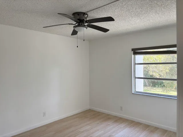 an empty room with a window and a ceiling fan