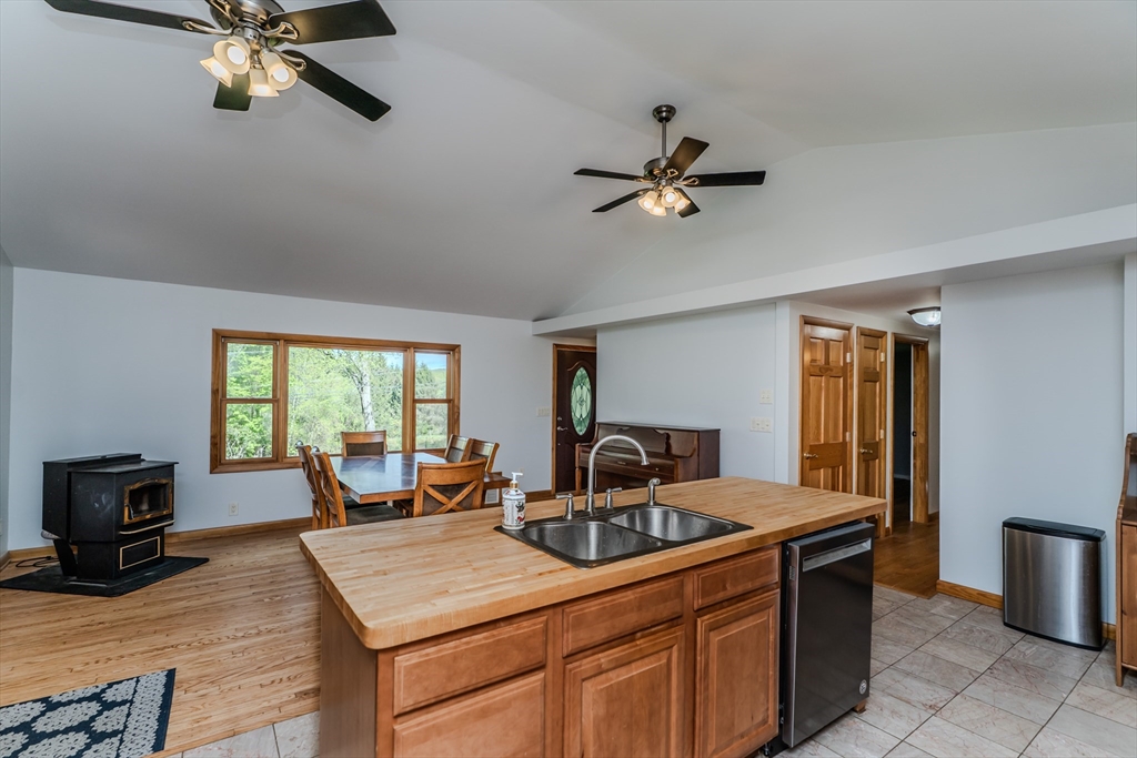 48 Ames Road Hampden, MA 01036 - Photo 28 of 42 a kitchen with a stove a sink dishwasher and a fireplace with wooden floor