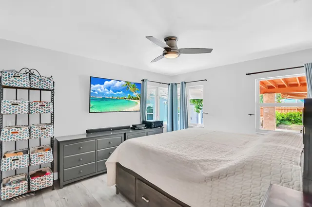 a bedroom with a bed and a flat tv screen on dresser