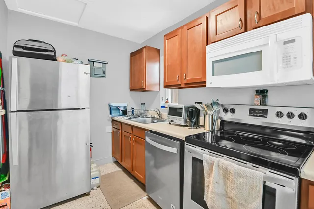 a kitchen with stainless steel appliances granite countertop a refrigerator a stove and a sink