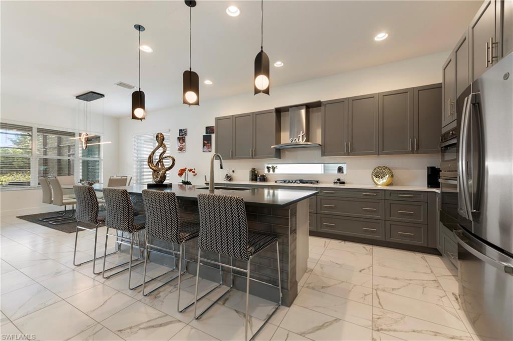 11488 Coronado Way Naples, FL 34120 - Photo 14 of 50 a kitchen with stainless steel appliances kitchen island granite countertop a sink a stove a refrigerator and cabinets