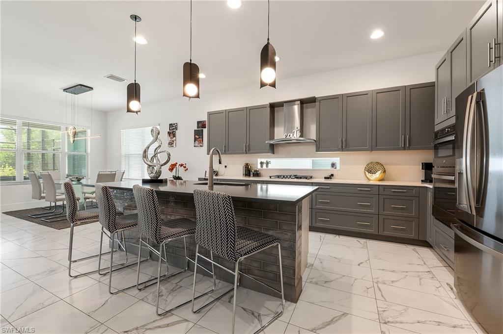 11488 Coronado Way Naples, FL 34120 - Photo 16 of 50 a kitchen with stainless steel appliances granite countertop a stove a sink a refrigerator a microwave oven with a dining table and chairs