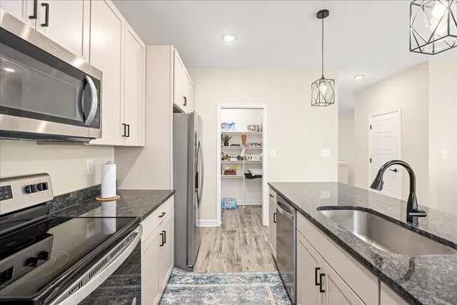 a kitchen with stainless steel appliances granite countertop a sink a stove and a wooden floors