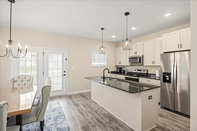 a kitchen with stainless steel appliances a refrigerator a stove a sink and white cabinets