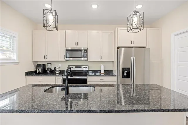 a kitchen with stainless steel appliances granite countertop a sink refrigerator and microwave