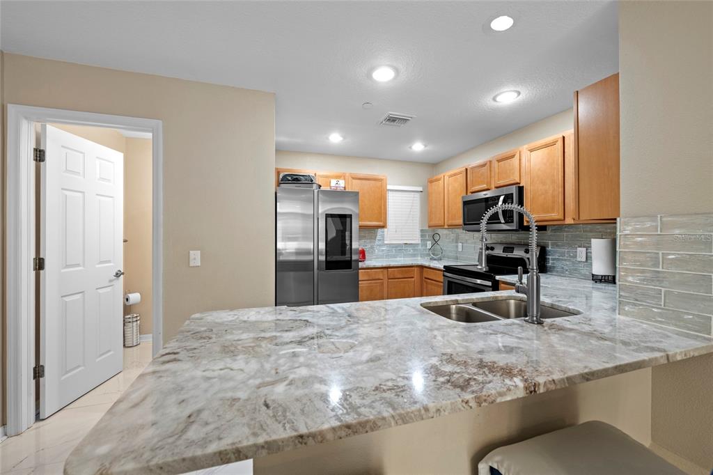8825 White Sage Loop Lakewood Ranch, FL 34202 - Photo 15 of 33 a kitchen with stainless steel appliances kitchen island granite countertop a sink and cabinets