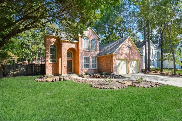 a front view of a house with a garden and trees