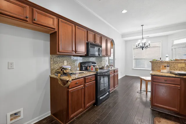 a kitchen with stainless steel appliances granite countertop a stove top oven a sink dishwasher and a refrigerator with wooden floor