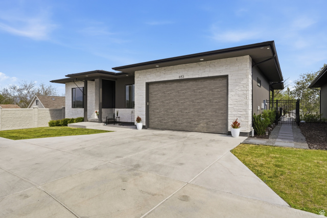 653 East Vandalay Lane Draper, UT 84020 - Photo 3 of 61 Contemporary exterior featuring stacked stone accents, a wood-finish garage door, and flat rooflines