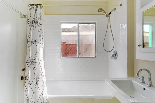 a bathroom with a bathtub a shower and a window
