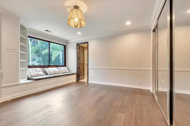 a view of empty room with wooden floor and fan