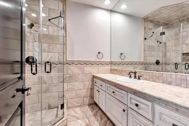 a bathroom with a granite countertop sink mirror and shower
