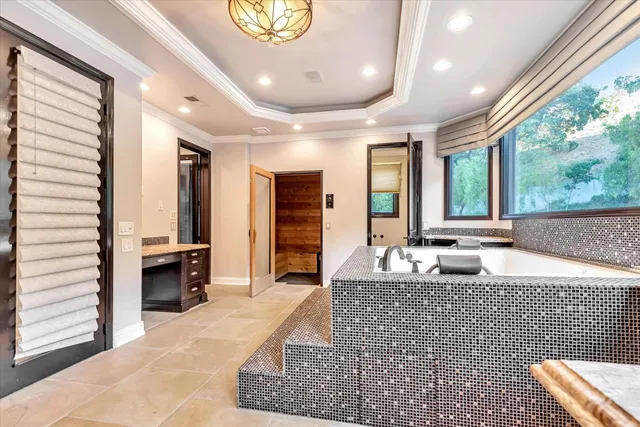 a large bedroom with a large bed a chandelier and large window