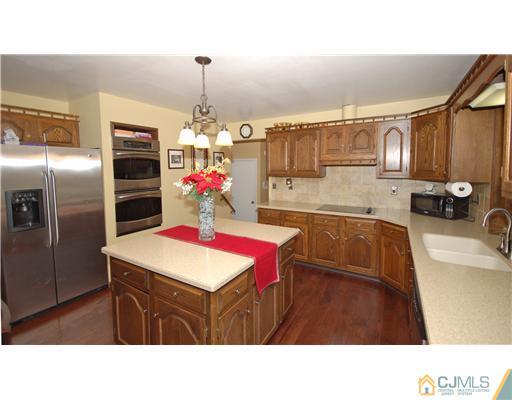 196 Friendship Road Cranbury, NJ 08512 - Photo 22 of 25 a kitchen with stainless steel appliances kitchen island granite countertop a sink dishwasher a refrigerator with wooden cabinets