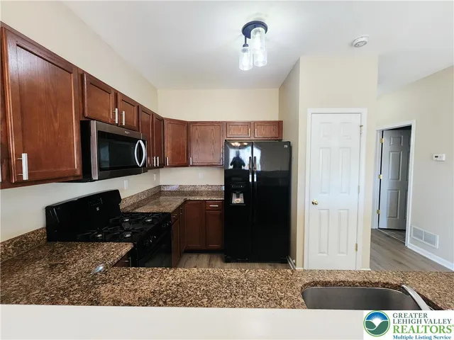 a living room with stainless steel appliances kitchen island granite countertop a refrigerator and a stove top oven