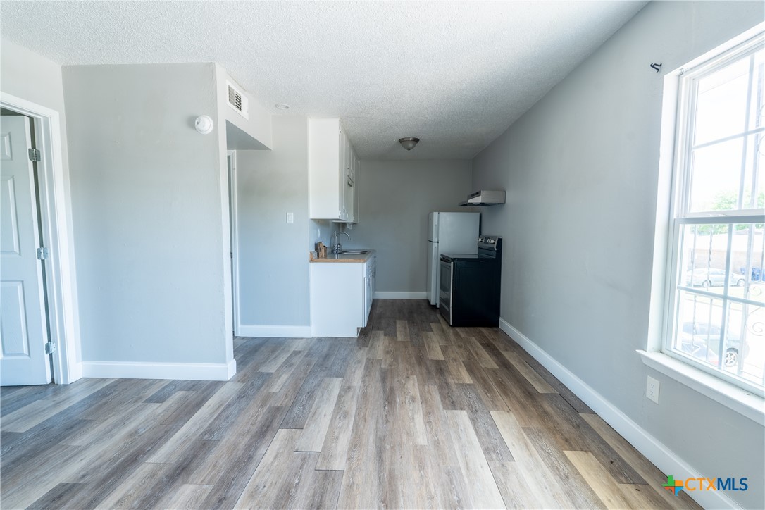 512 Sunset Lane, Unit AD Copperas Cove, TX 76522 - Photo 5 of 23 a view of a kitchen with wooden floor and a refrigerator