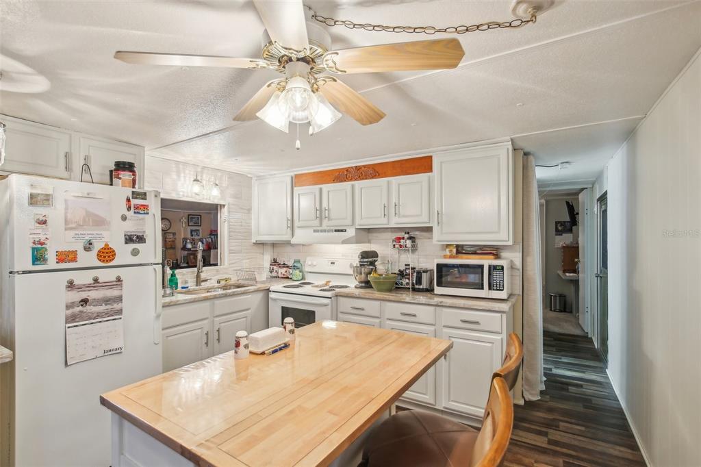 1600 Old Coachman Rd., Unit 311 Clearwater, FL 33765 - Photo 14 of 27 a kitchen with stainless steel appliances granite countertop a sink dishwasher and white cabinets with wooden floor