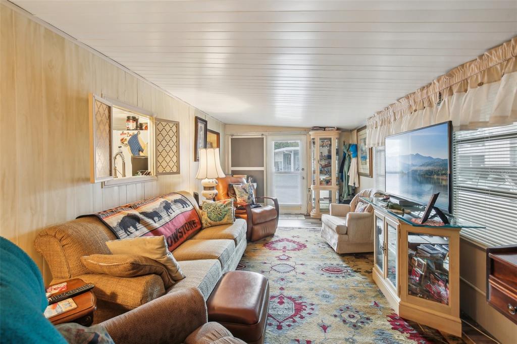 1600 Old Coachman Rd., Unit 311 Clearwater, FL 33765 - Photo 6 of 27 a living room with furniture a flat screen tv and a floor to ceiling window