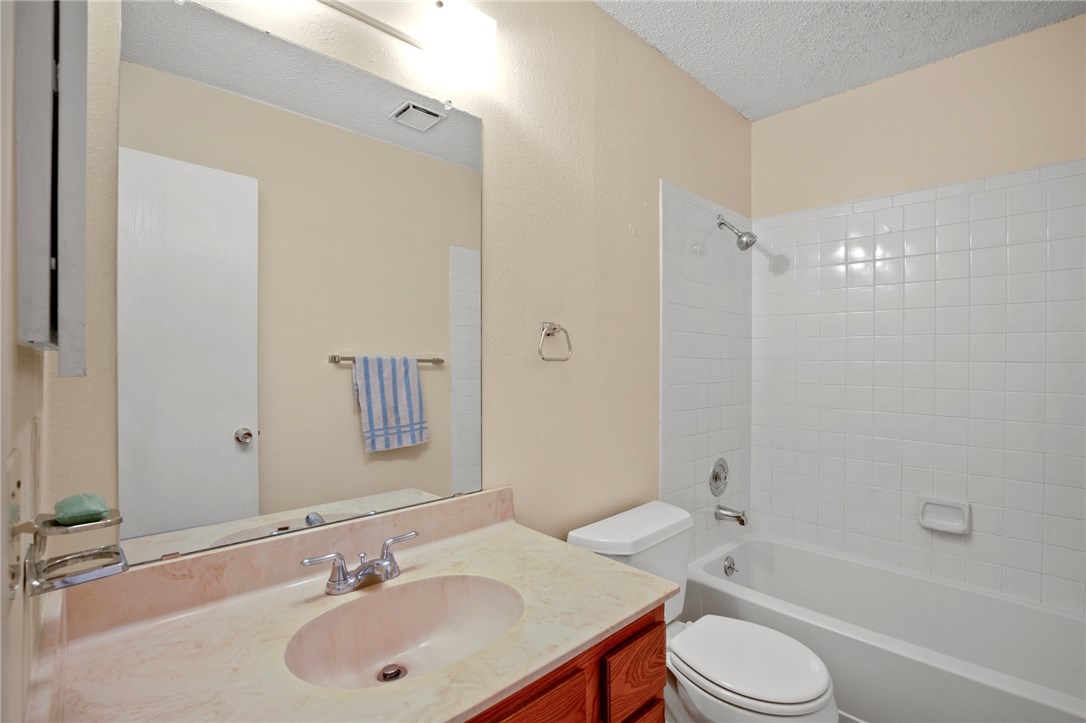 12213 Tyson Cove, Unit B Austin, TX 78758 - Photo 13 of 15 a bathroom with a toilet a sink a mirror a bathtub and shower