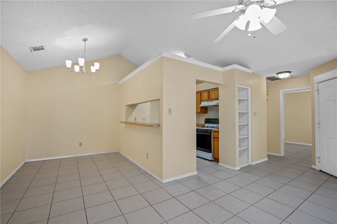 12213 Tyson Cove, Unit B Austin, TX 78758 - Photo 4 of 15 an empty room with chandelier fan and kitchen view