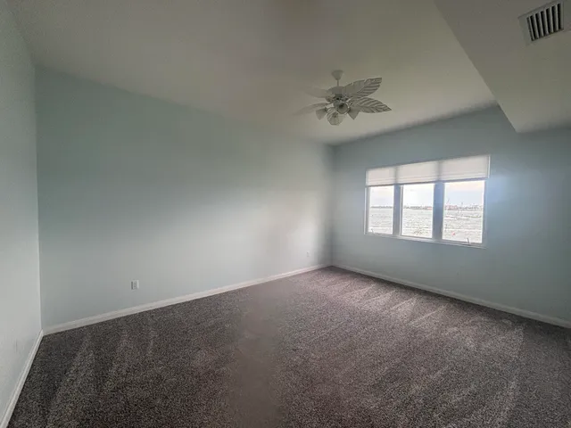 an empty room with a window and a ceiling fan