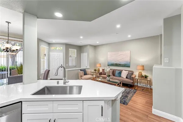 a kitchen with sink refrigerator and couches with wooden floor