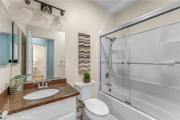 a bathroom with a granite countertop sink toilet mirror and shower