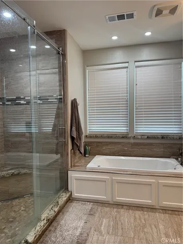 a bathroom with a granite countertop sink double vanity tub and mirror