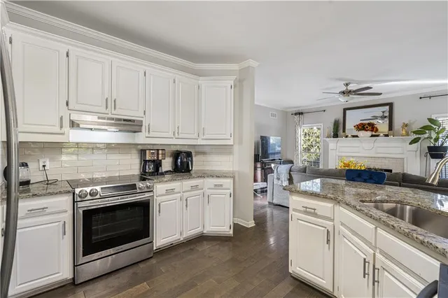 a kitchen with stainless steel appliances granite countertop a refrigerator a sink a stove and white cabinets