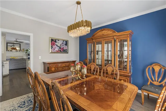 a kitchen with granite countertop a stove a sink dishwasher a dining table and chairs with wooden floor