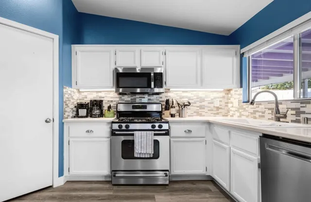 a kitchen with stainless steel appliances white cabinets and a window