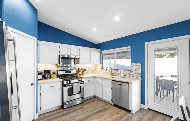 a kitchen with stainless steel appliances granite countertop a refrigerator a stove and a wooden floors