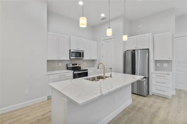 a kitchen that has a lot of white cabinets and stainless steel appliances