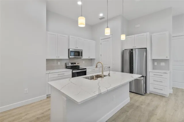 a kitchen that has a lot of white cabinets and stainless steel appliances