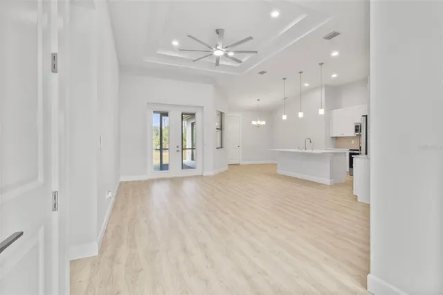 a view of an empty room and kitchen view with wooden floor