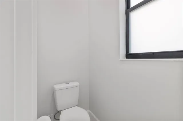a white toilet sitting next to a white wall