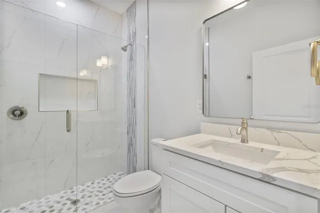 a bathroom with a granite countertop sink a toilet and shower