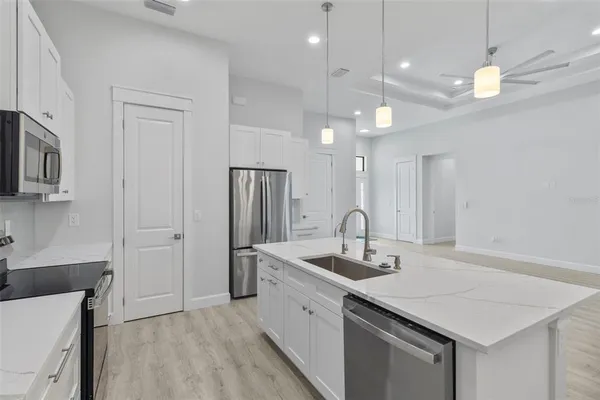a kitchen with stainless steel appliances granite countertop a sink a refrigerator and a white cabinets