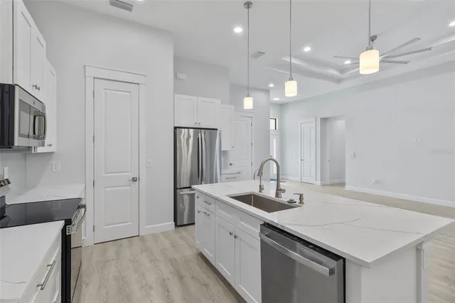 a kitchen with stainless steel appliances granite countertop a sink a refrigerator and a white cabinets