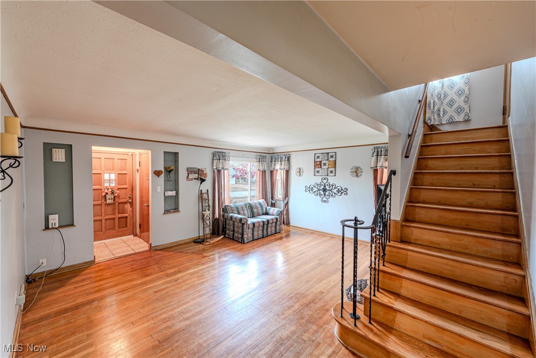 6445 Stanbury Road Cleveland, OH 44129 - Photo 2 of 17 Living room with stairway, light wood-style floors, baseboards, and crown molding