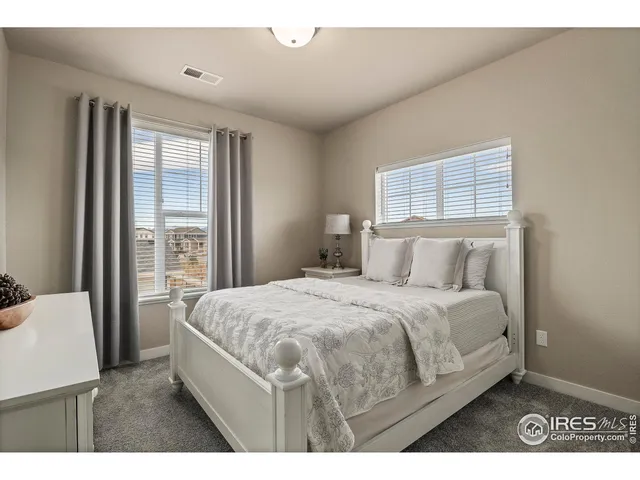 a bedroom with a bed a dresser and windows