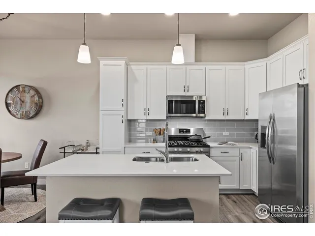 a kitchen with stainless steel appliances kitchen island granite countertop a sink a refrigerator and a granite counter tops